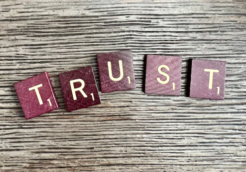 trust spelled with wooden letter blocks on a table