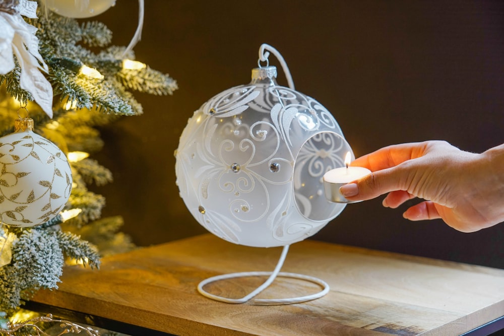 a person is holding a white ornament on a table