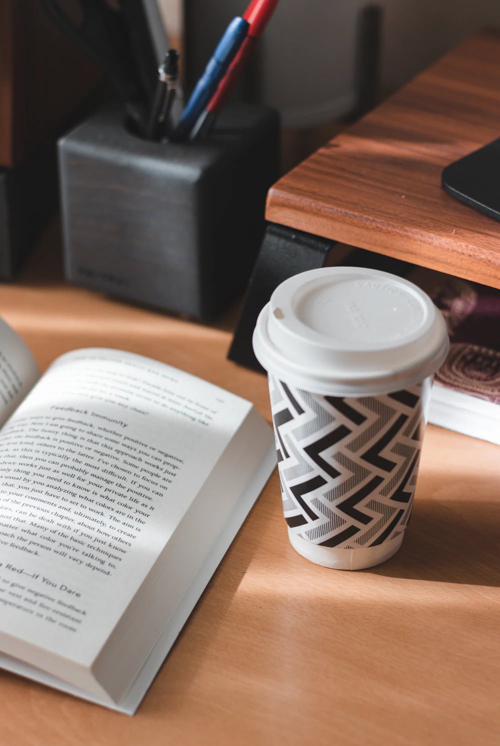 Open book and a cup of coffee on a wooden desk
