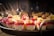 A tray filled with elegantly arranged small dessert cups featuring layers of white and red mousse, garnished with intricately designed chocolate pieces and wafers. The desserts are creatively presented and illuminated under soft, warm lighting, highlighting their vibrant colors and textures.