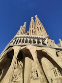 Bright daylight view of Barcelona’s Sagrada Familia cathedral with tourists walking nearby.