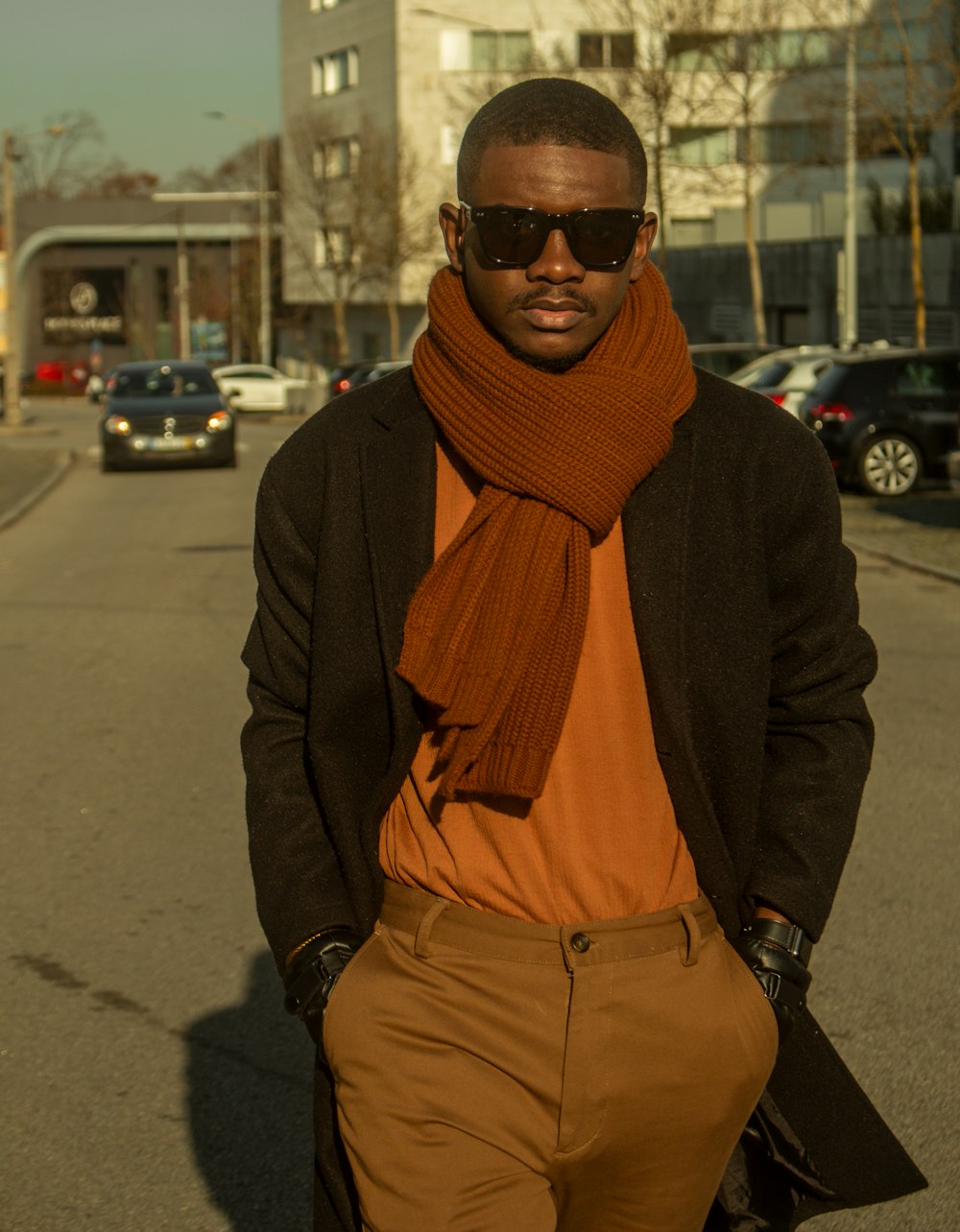 a man wearing a scarf and sunglasses walking down a street
