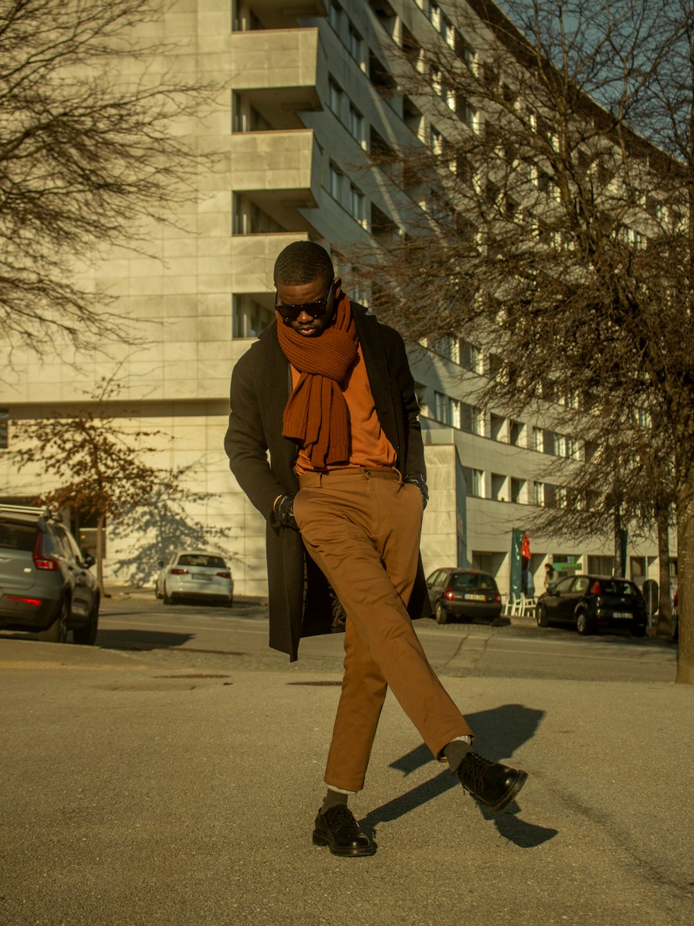 Un uomo in pantaloni marroni e una sciarpa arancione