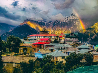 a rainbow shines in the sky over a mountain village