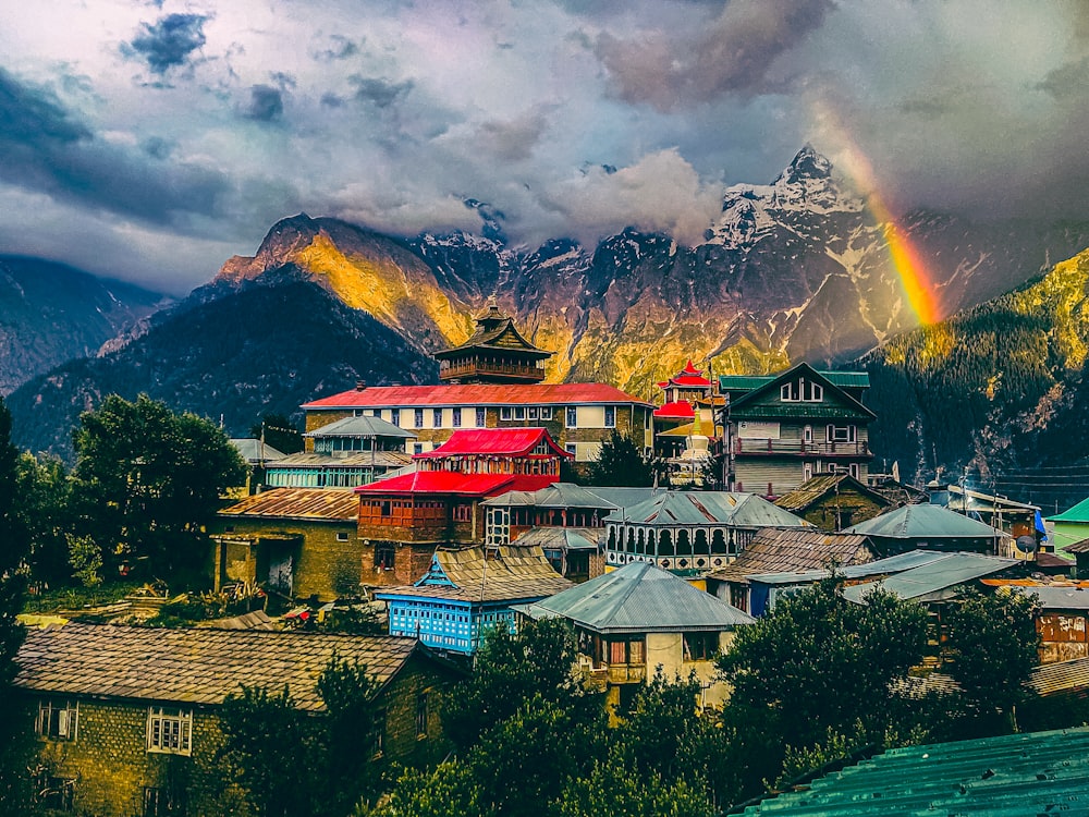 a rainbow shines in the sky over a mountain village