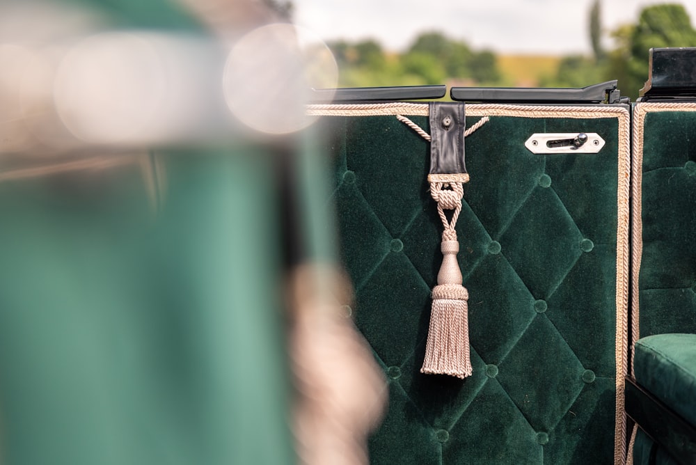 a green chair with a tassel hanging from the back of it