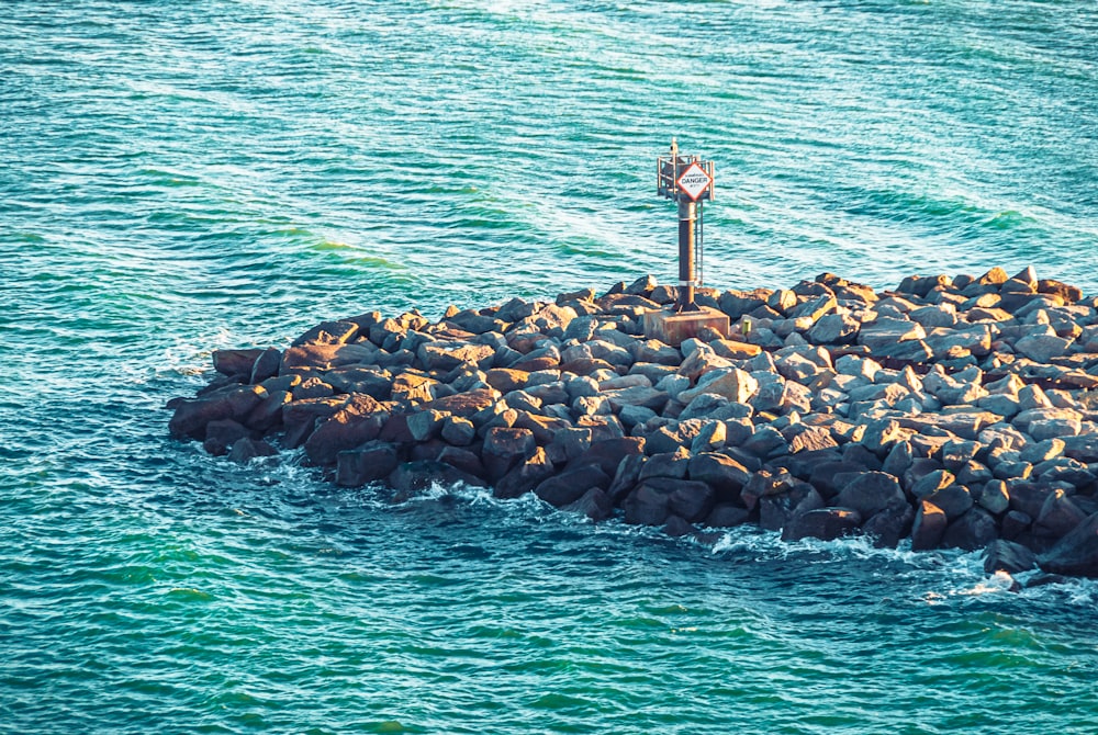 a clock on a rock island in the middle of the ocean