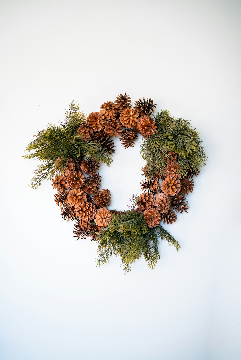 a wreath made of pine cones and evergreen branches