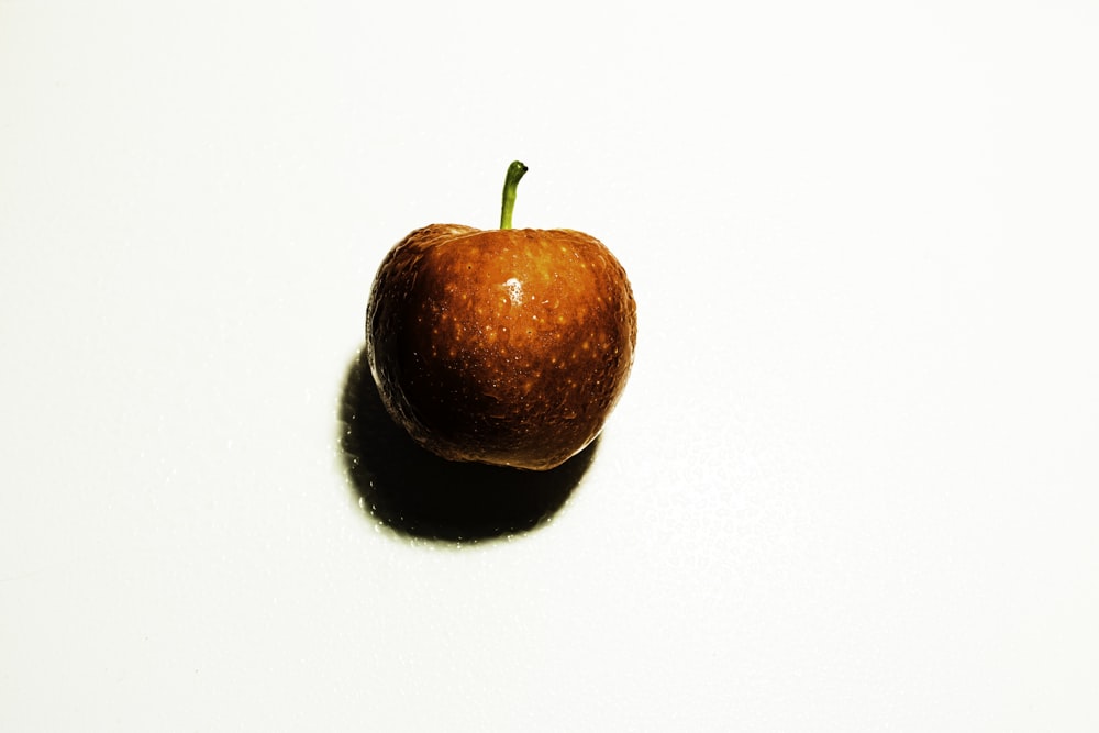 une pomme posée sur une table blanche