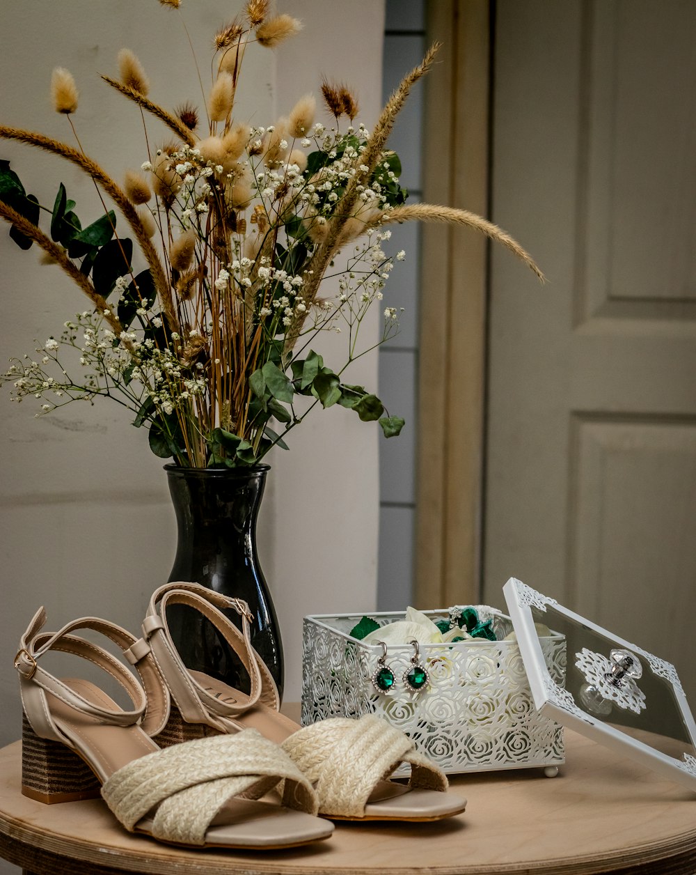 a table topped with a vase filled with flowers and a pair of shoes