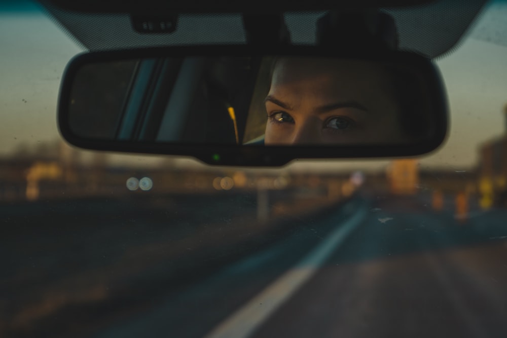 a woman's reflection in a rear view mirror