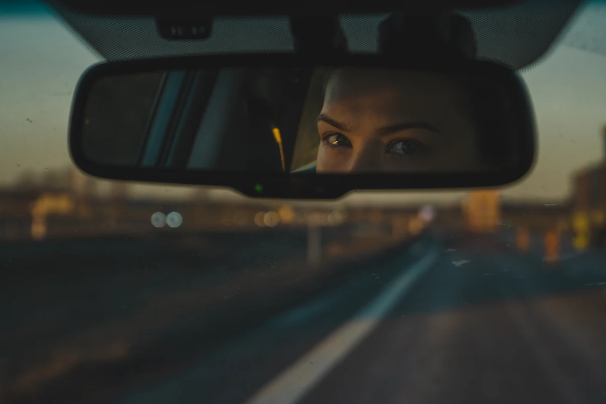 A driver's eyes in the rear view mirror at dusk