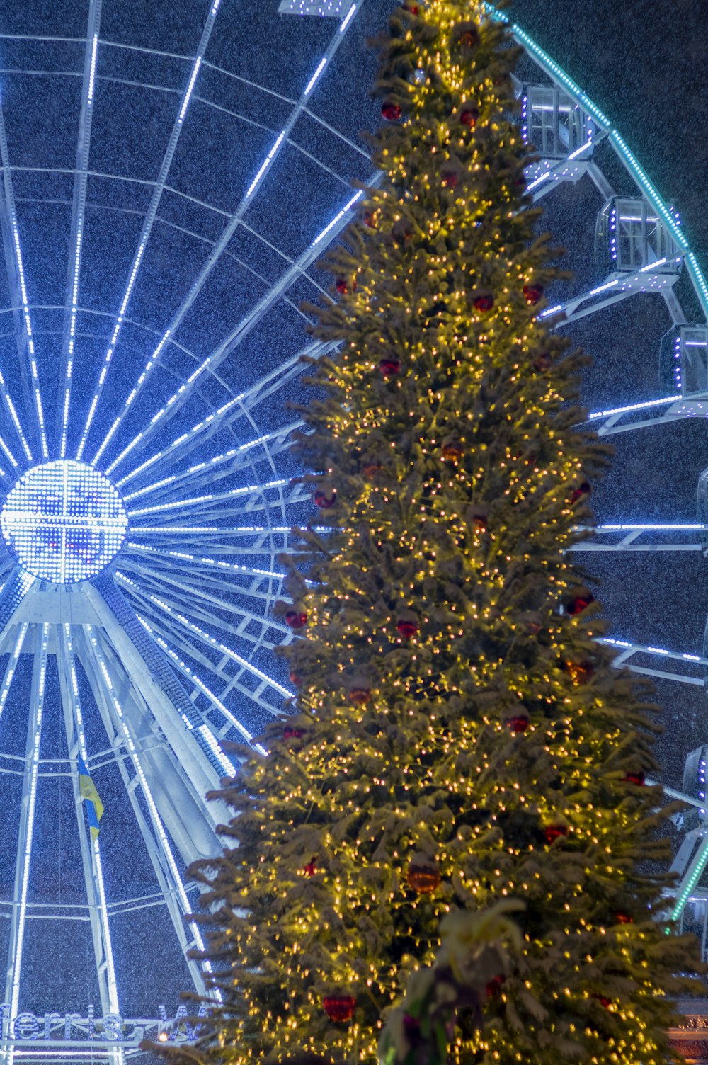 a large christmas tree in front of a ferris wheel