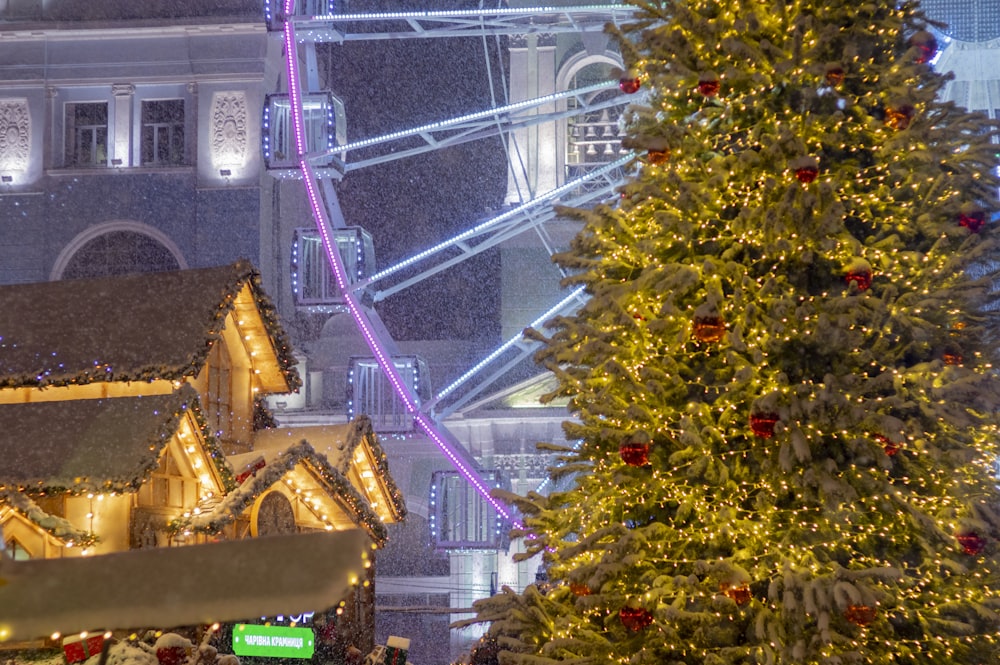 a large christmas tree in front of a ferris wheel