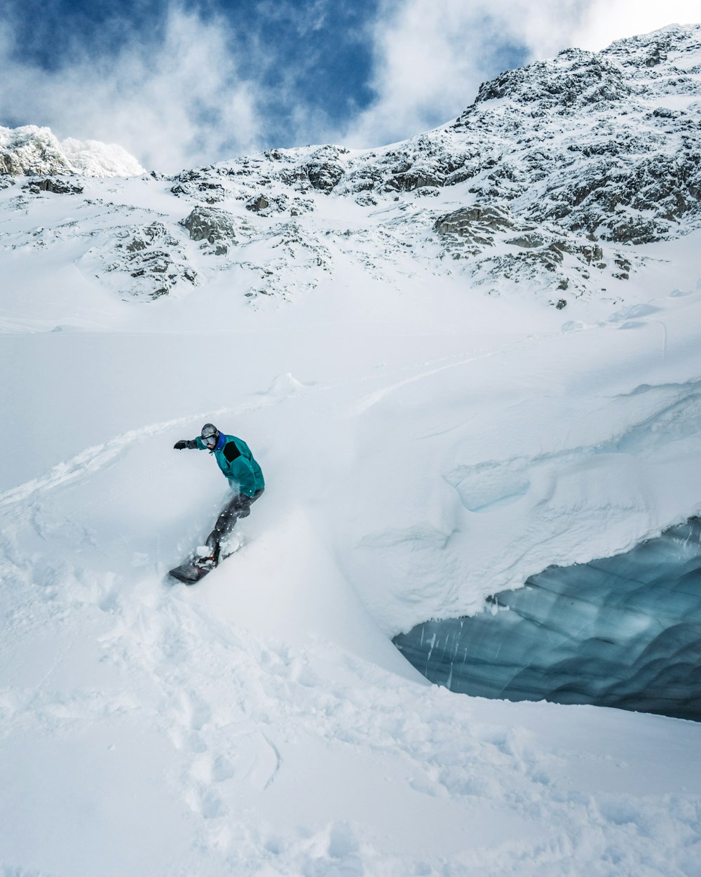 a man riding a snowboard down the side of a snow covered slope