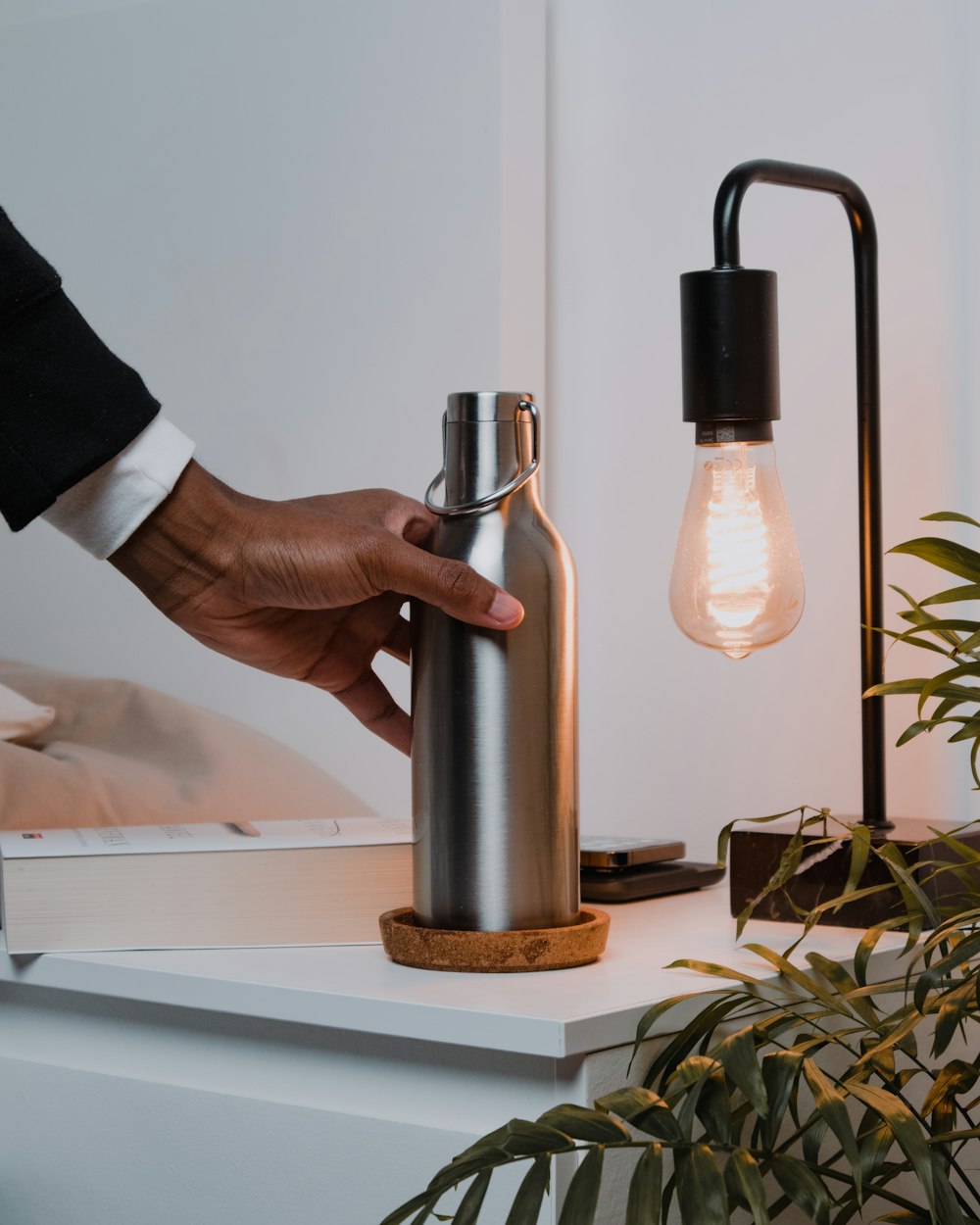 a person holding a light bulb next to a lamp