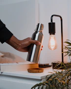 a person holding a light bulb next to a lamp