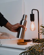 a person holding a light bulb next to a lamp