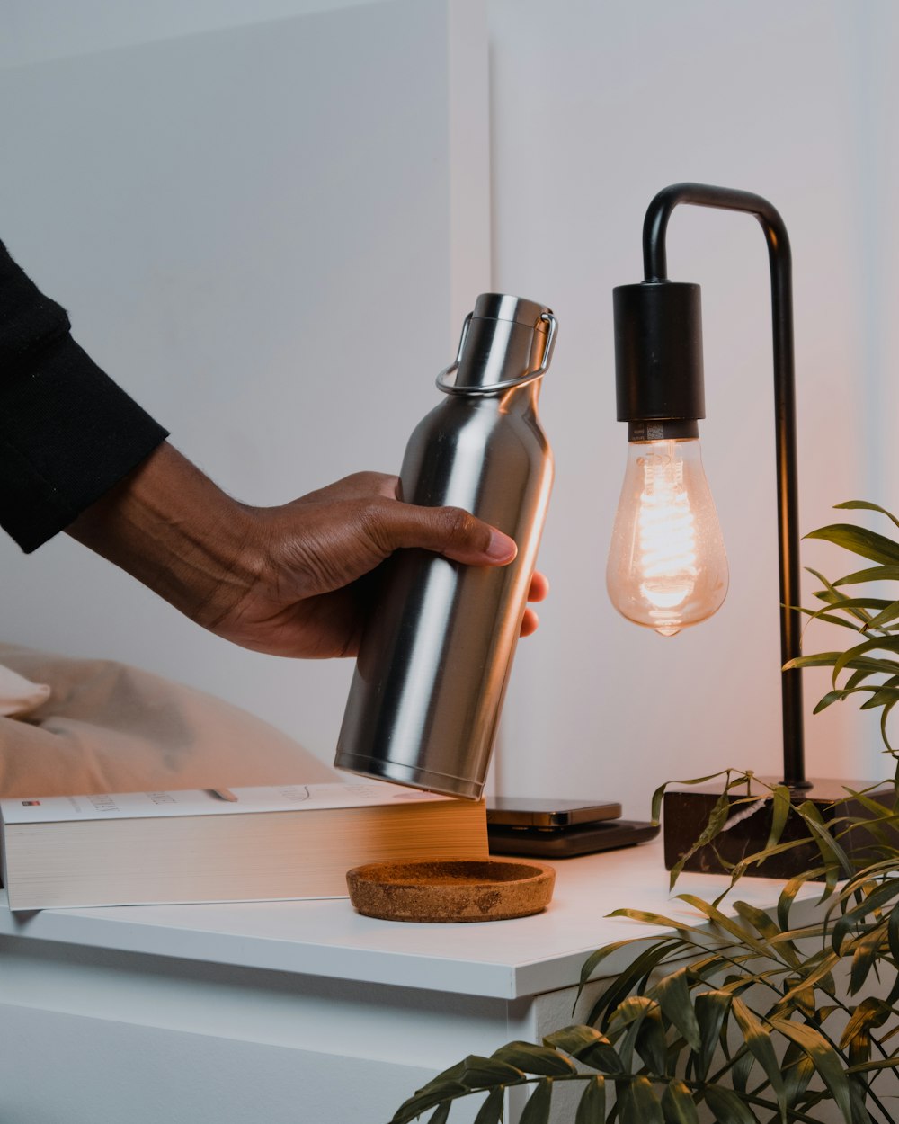 a person holding a light bulb next to a lamp