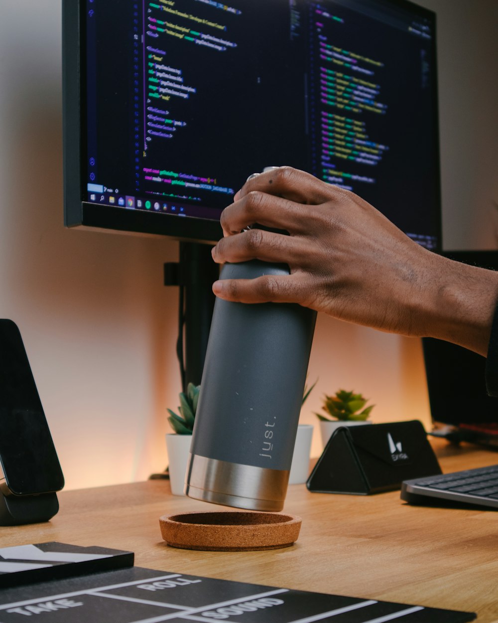 a person holding a coffee cup in front of a computer