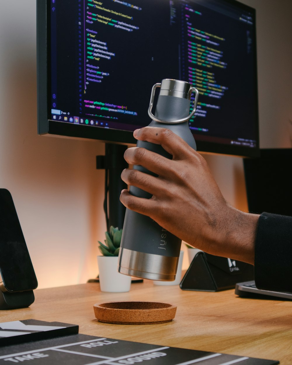 a person holding a coffee cup in front of a computer