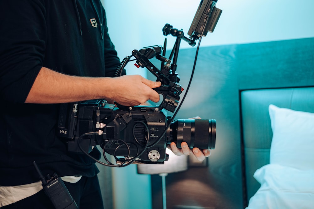 a man holding a camera in front of a bed