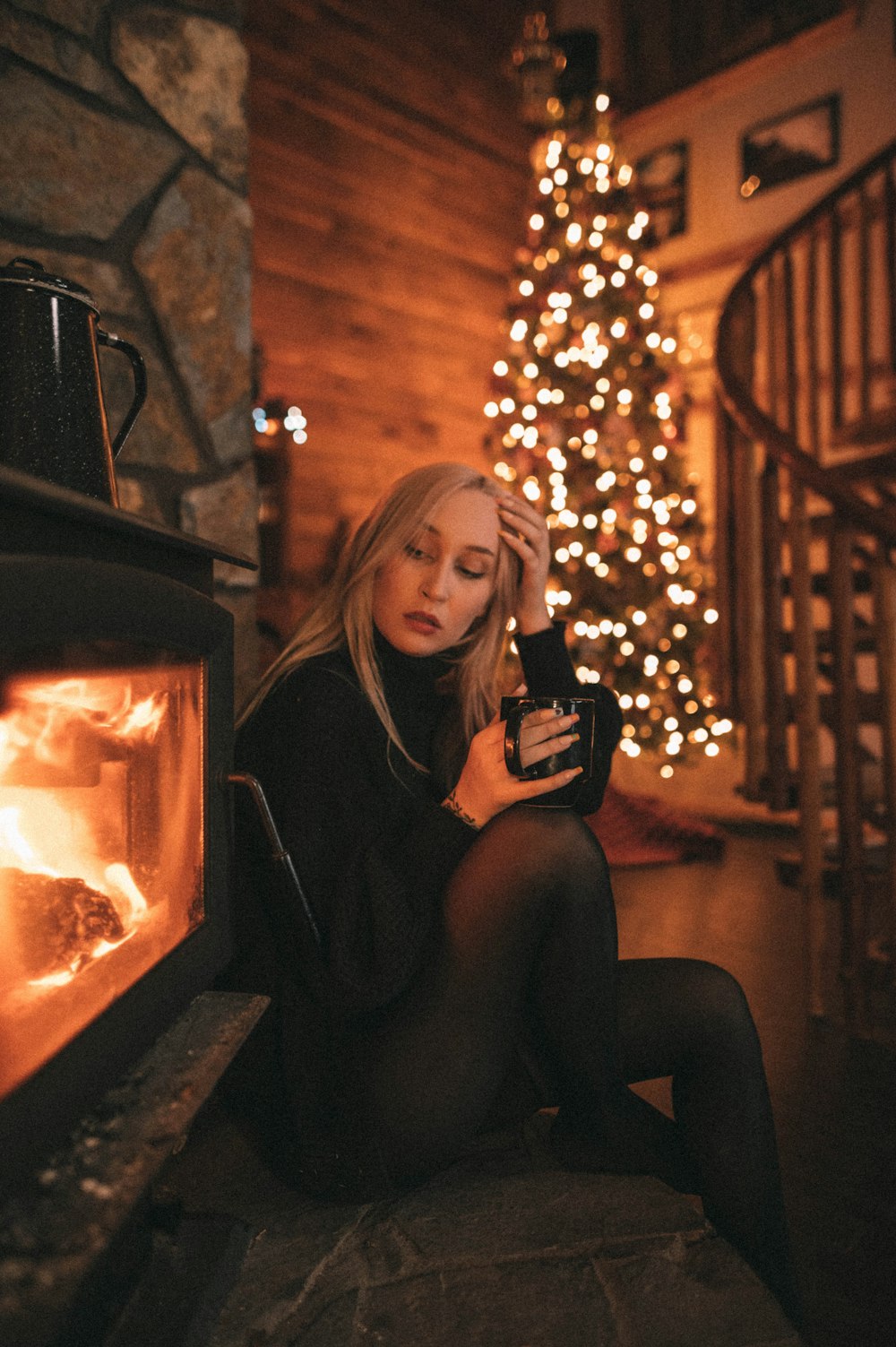 a woman sitting in front of a fireplace holding a camera