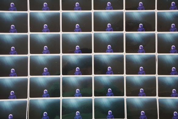 A grid of identical images featuring a person wearing a blue space suit with a helmet, set against a dark, ethereal background with beams of light shining through.