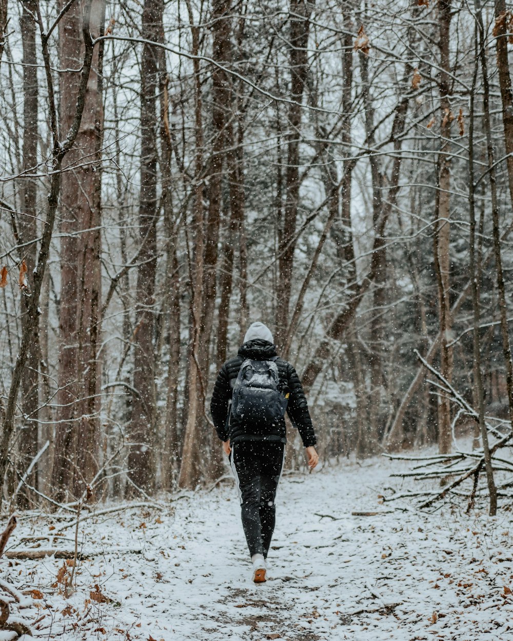 a man walking through a forest in the snow