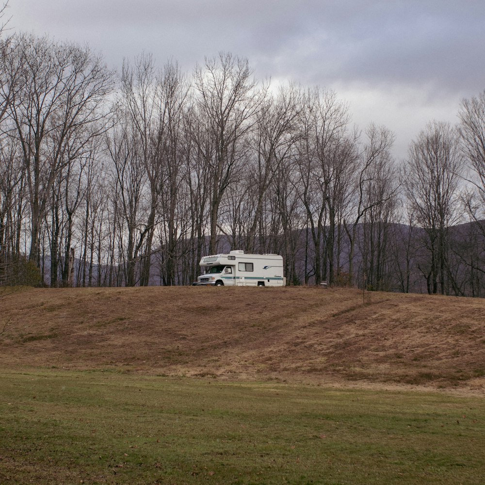 a white rv parked on top of a grass covered hill