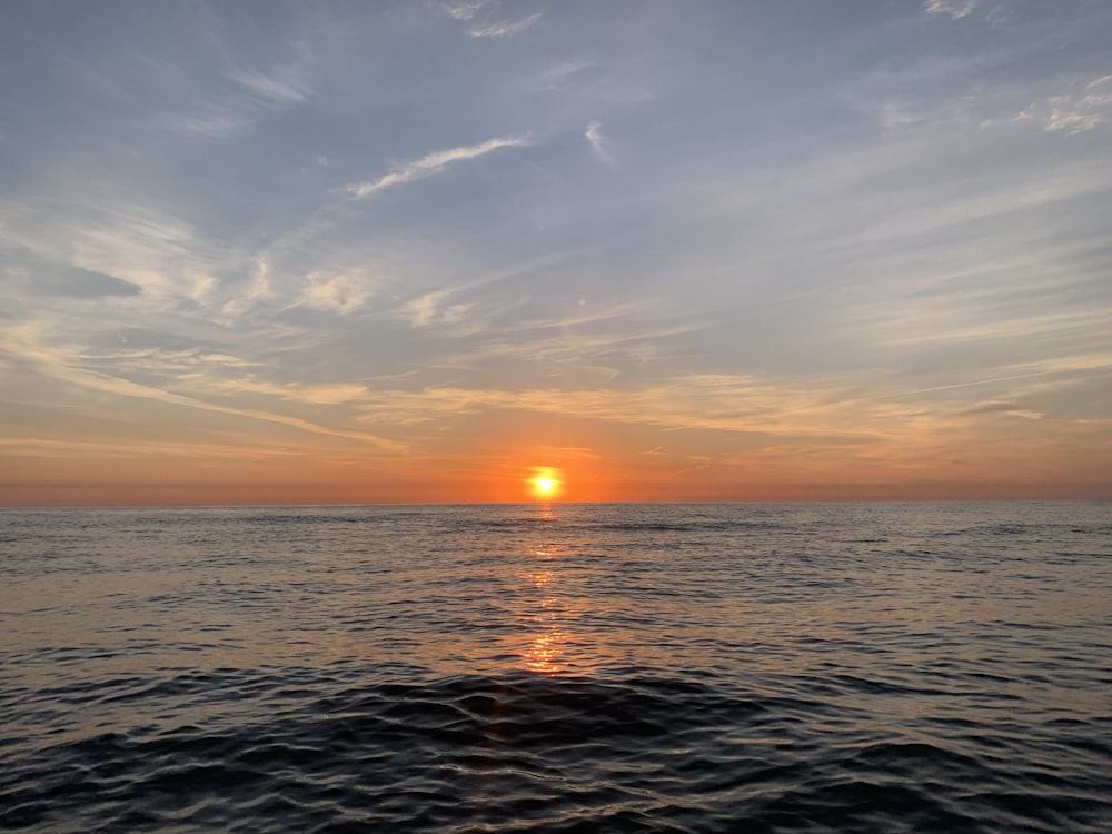 the sun is setting over the ocean as seen from a boat