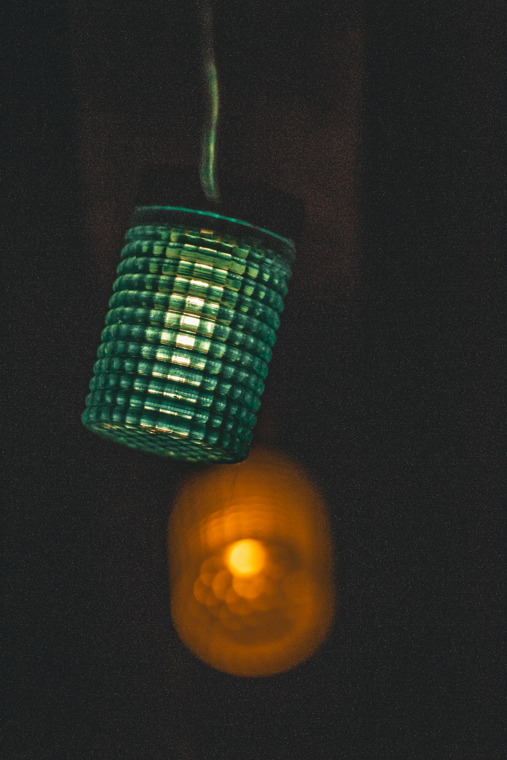 a green glass hanging from a hook in a dark room