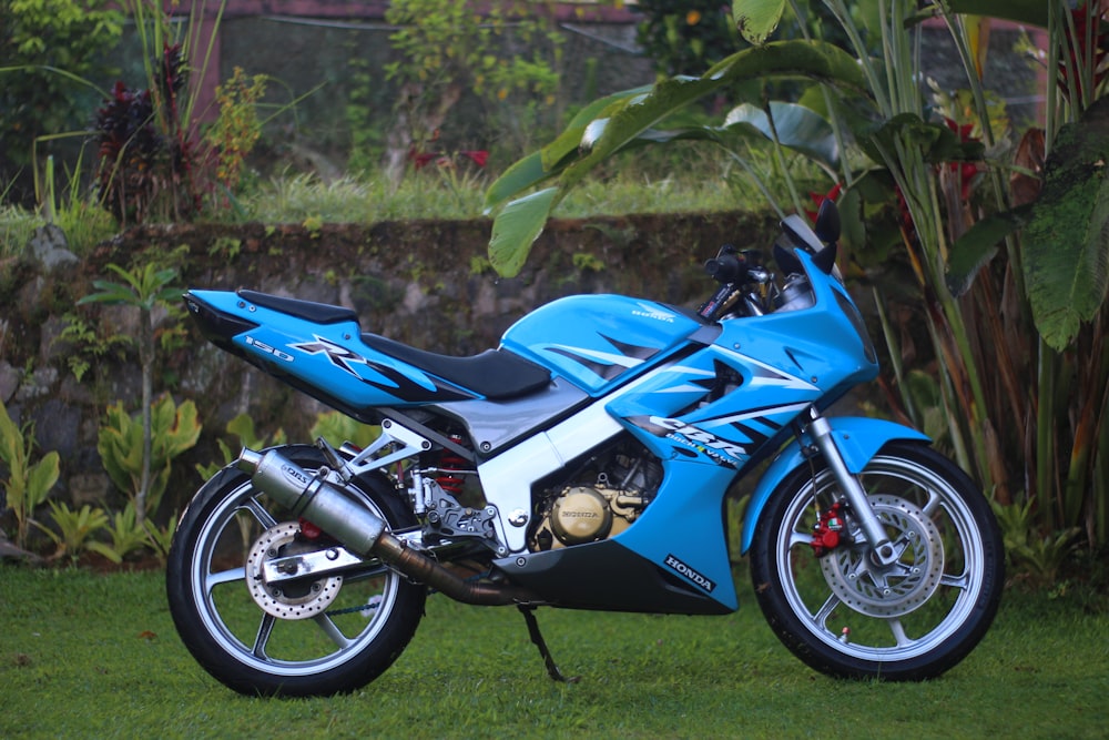 a blue motorcycle parked on top of a lush green field