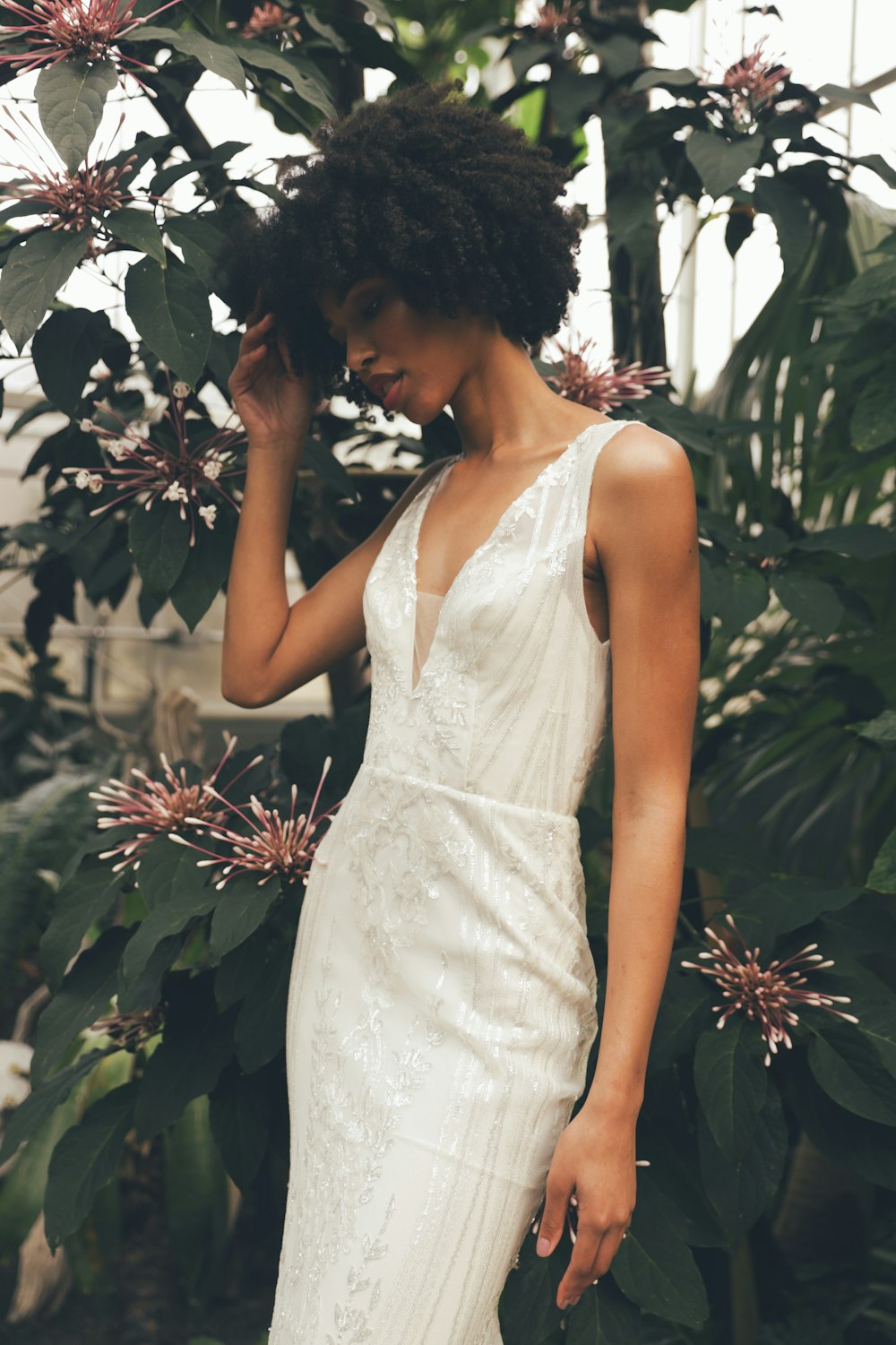 a woman in a white dress standing next to a tree