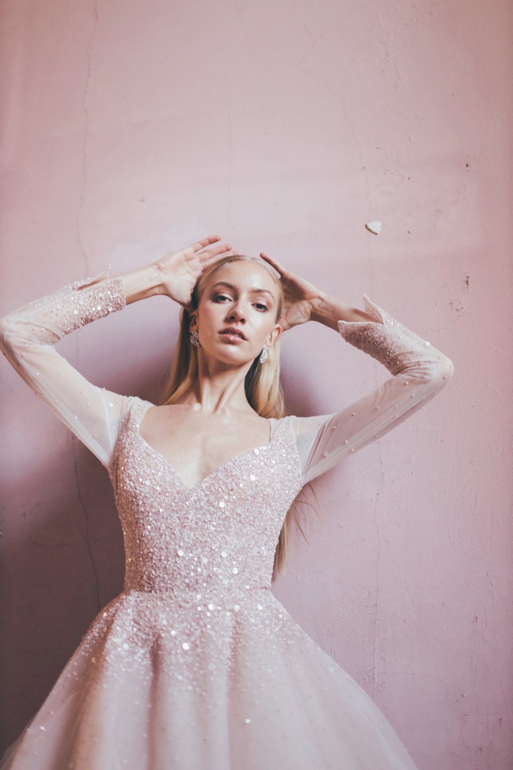 a woman in a white dress posing with her hands on her head