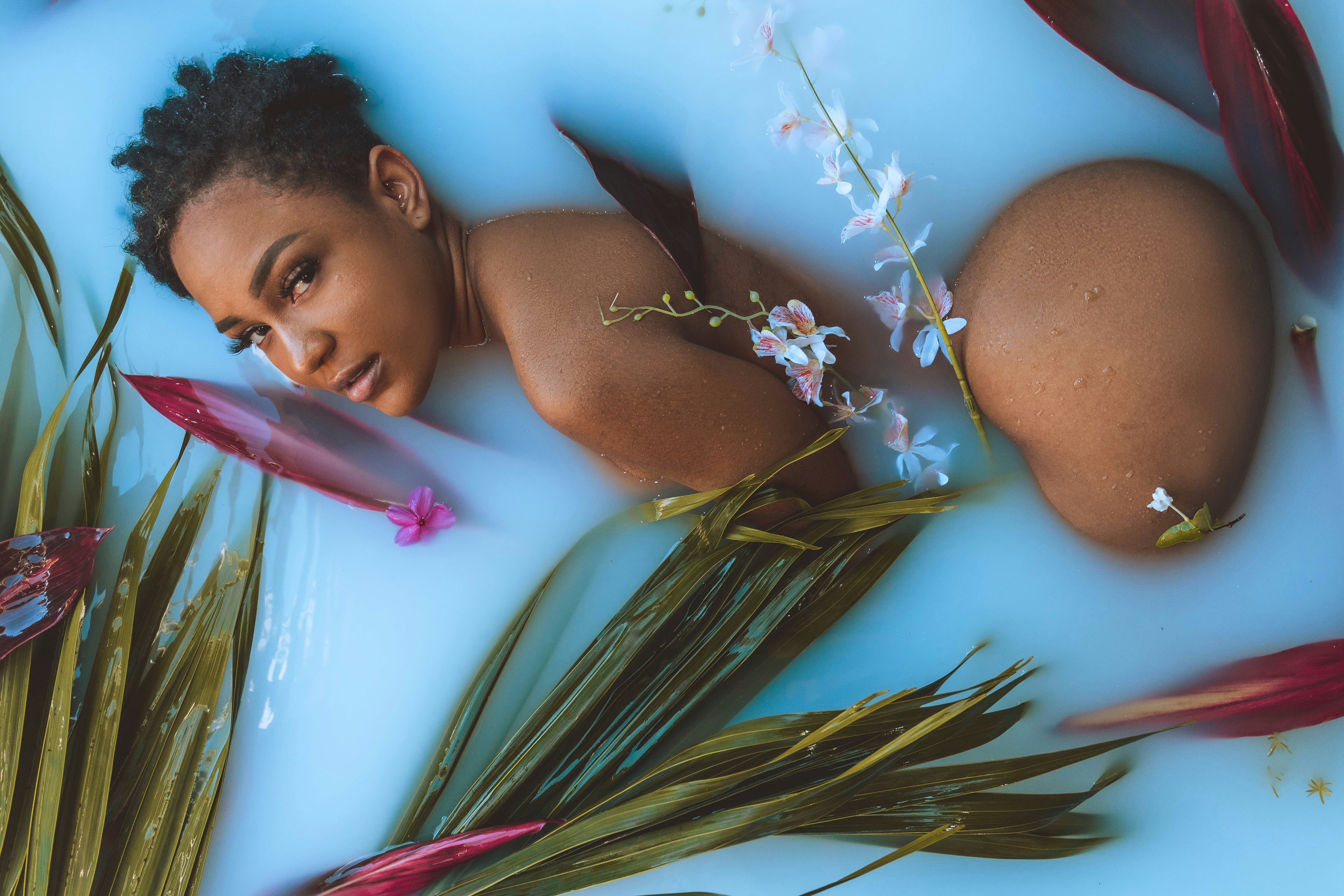 a woman laying in a pool of water surrounded by flowers