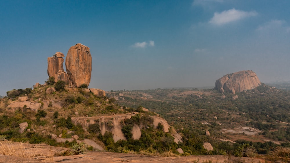 a large rock formation sitting on top of a lush green hillside