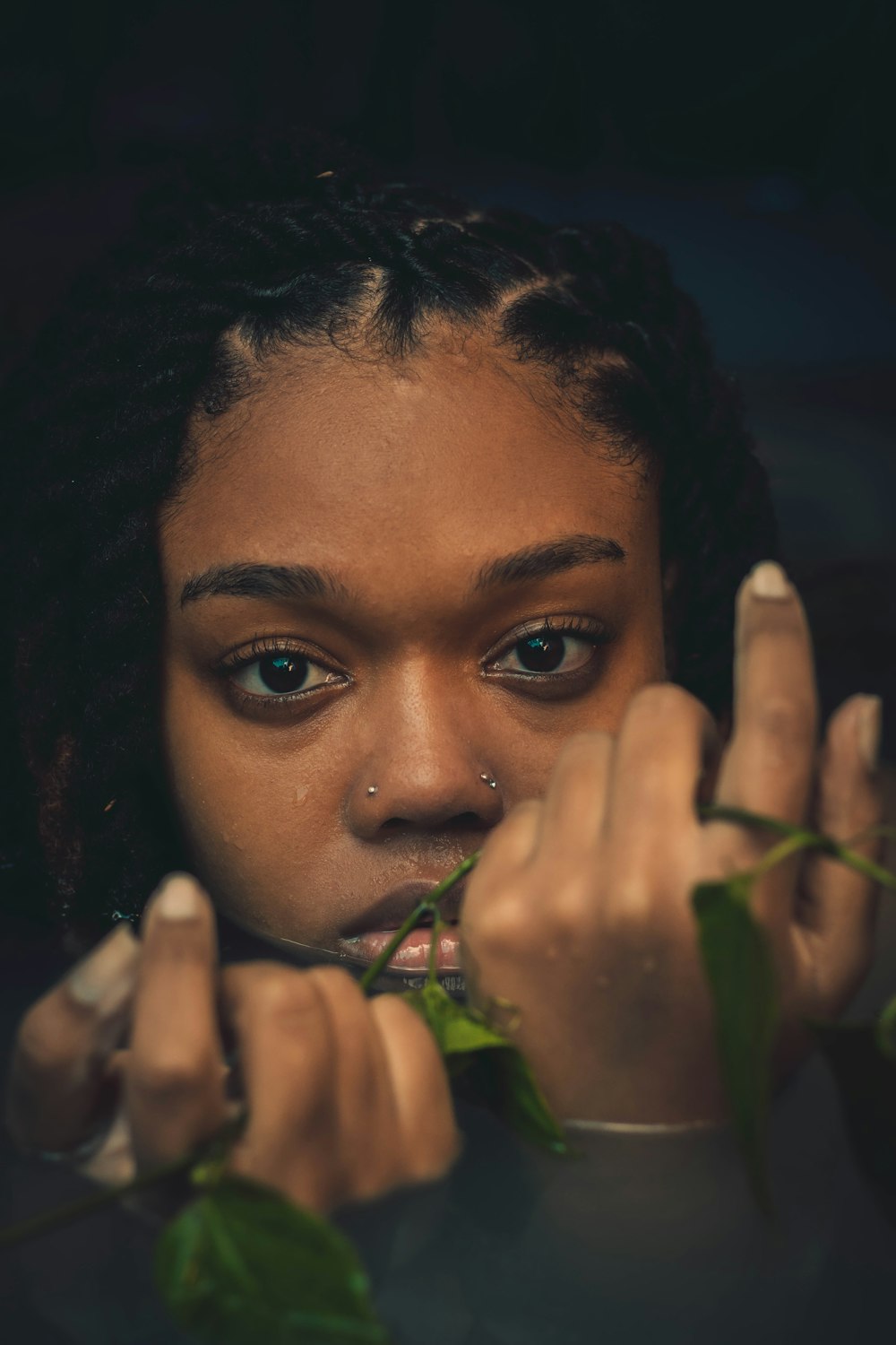 a young woman holding a green plant in front of her face