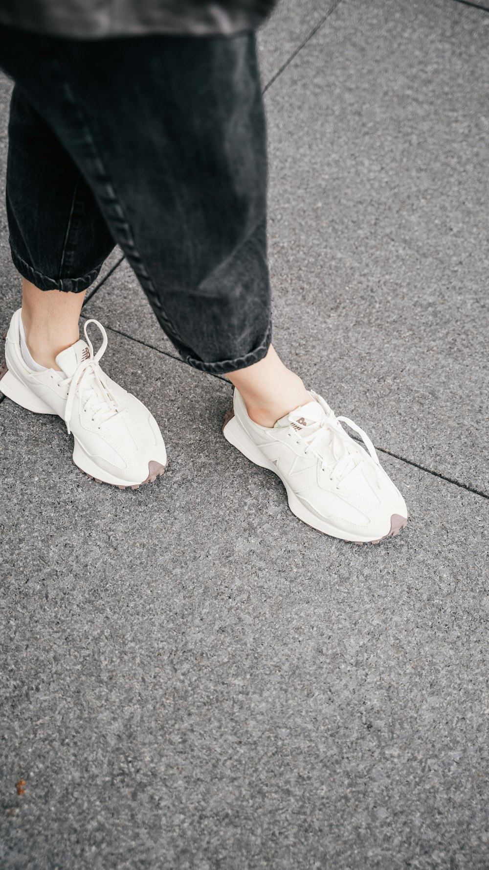 a person standing on a sidewalk wearing white sneakers