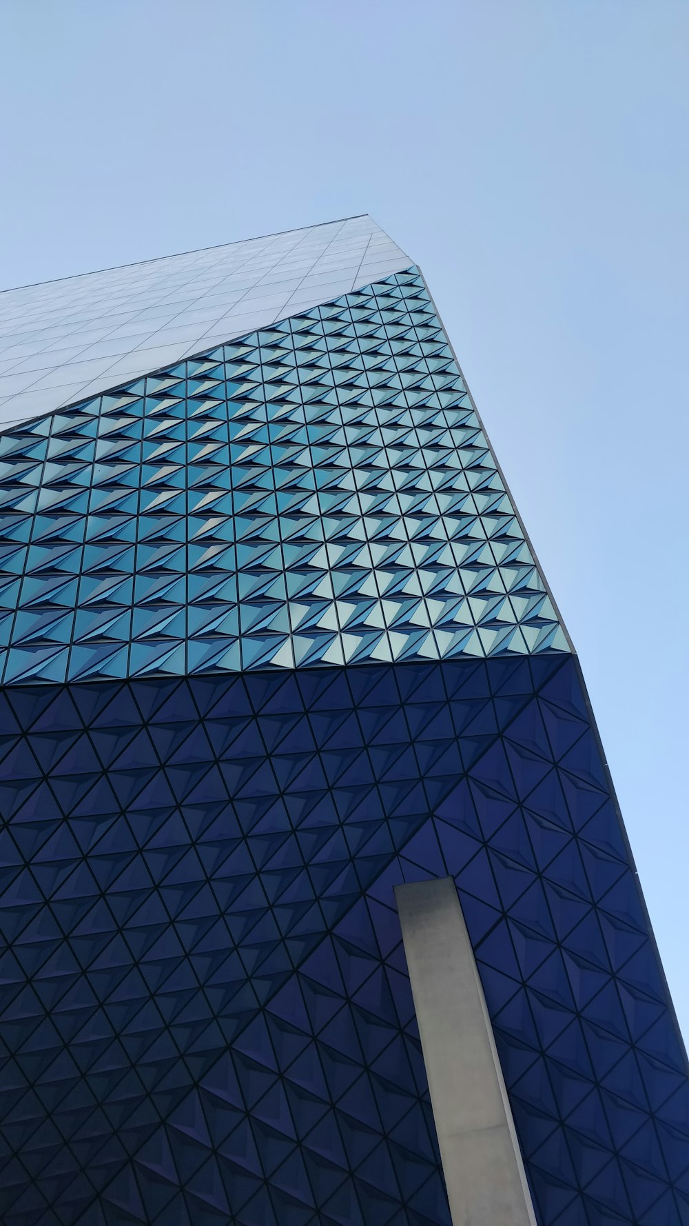 a tall blue building with a sky background