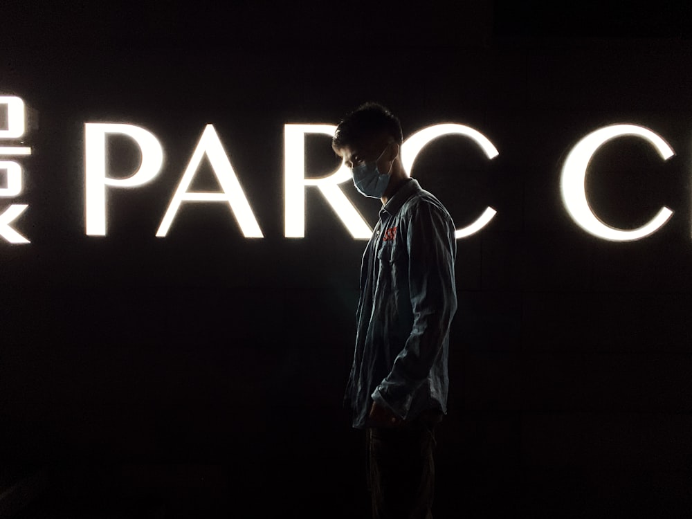 a man standing in front of a neon sign