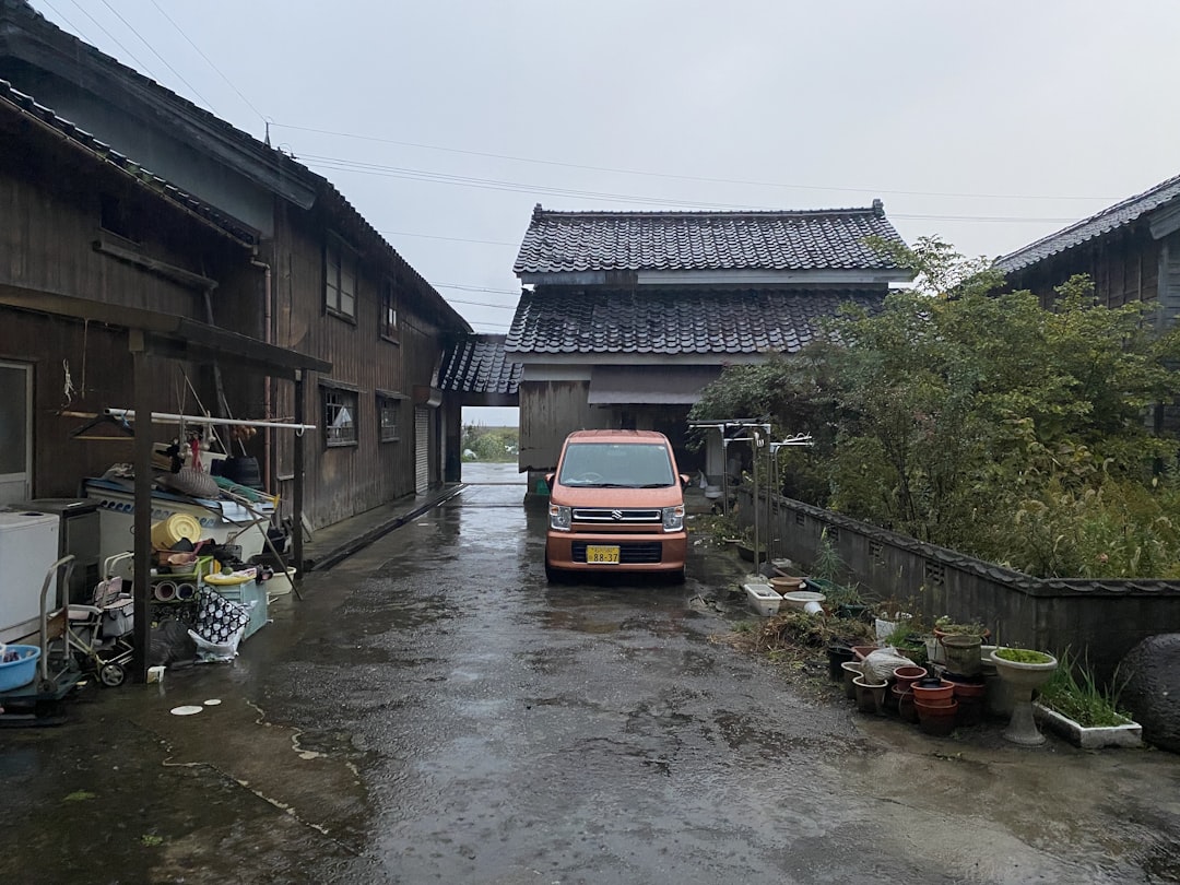 a bus that is parked on the side of a river, Driveway of a ryokan in Ishikawa.