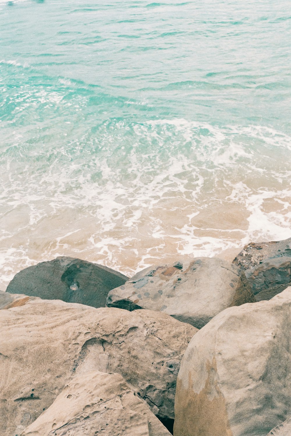 a person sitting on a rock near the ocean