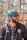 A person with a beard and sunglasses is wearing a turquoise headscarf and a jacket with a logo that reads 'Northeast United FC'. The individual appears to be outside, under natural light, with a blurred background of trees and structures.