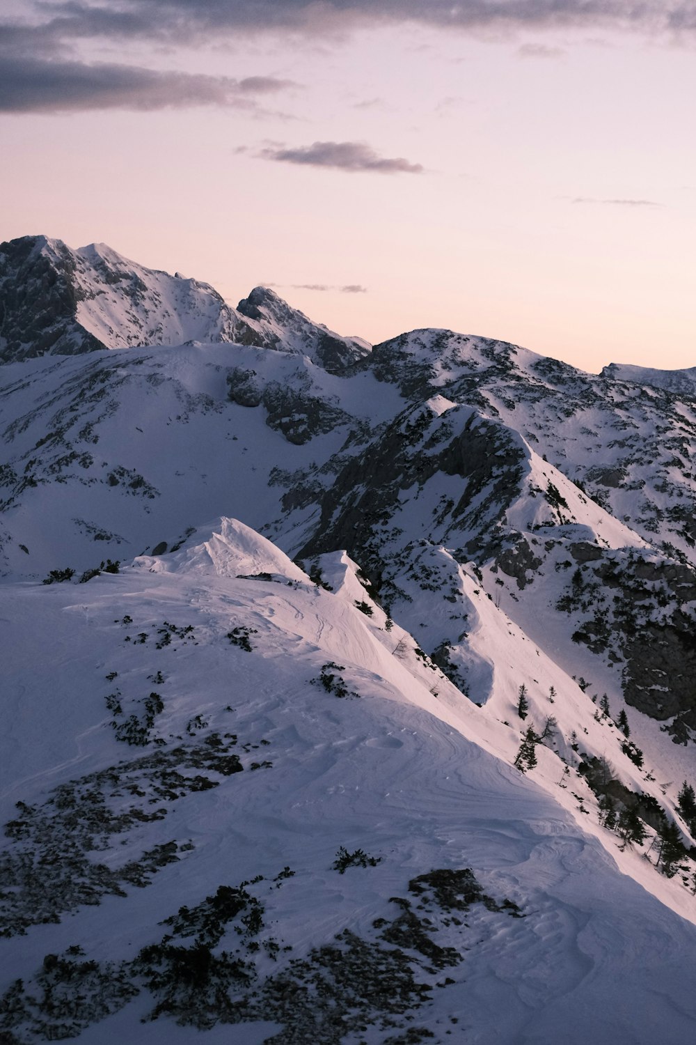 a mountain covered in snow under a cloudy sky