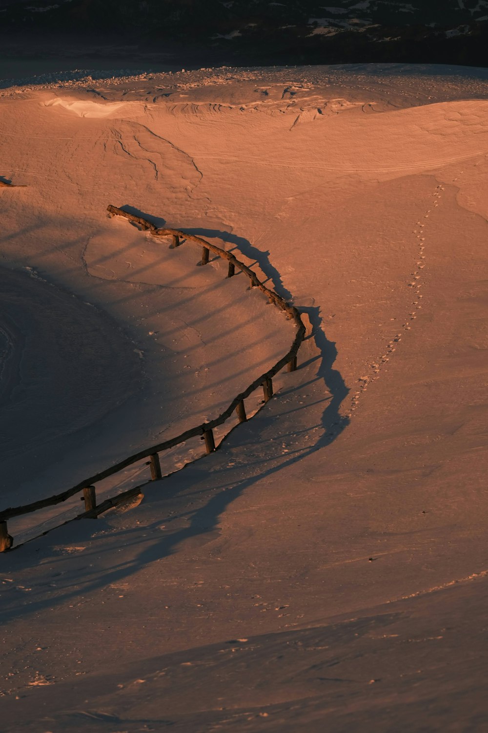 a snow covered field with a fence in the middle of it