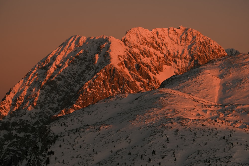 a mountain covered in snow at sunset