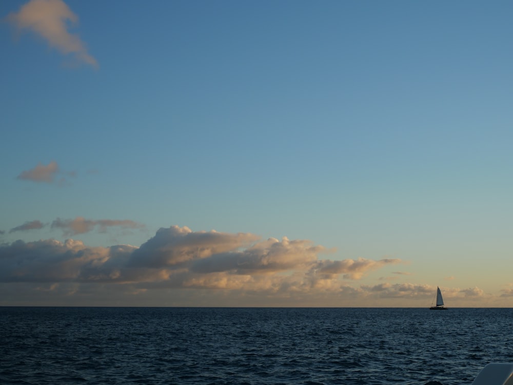 a sailboat sailing in the ocean at sunset