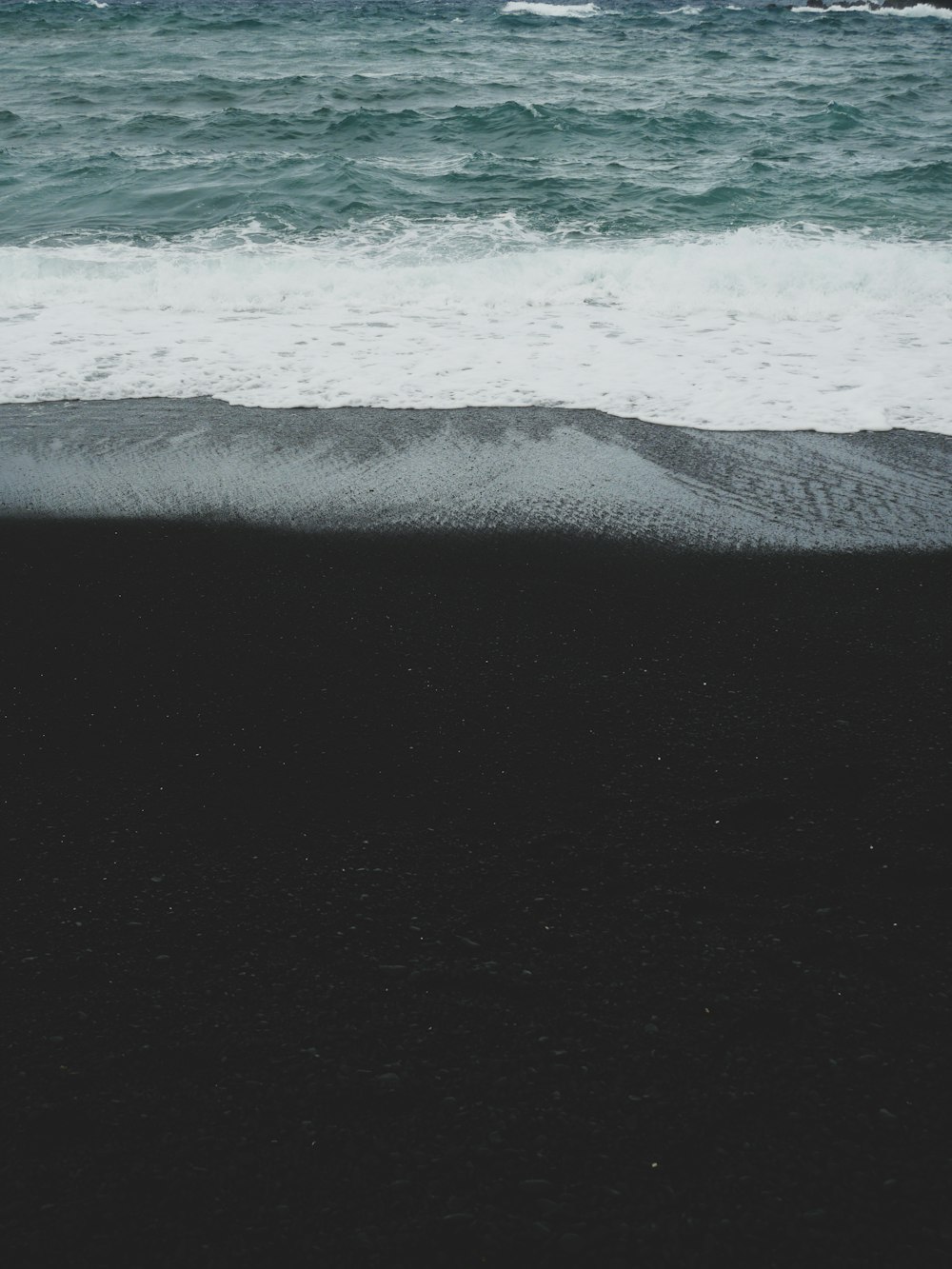 a black sand beach with the ocean in the background