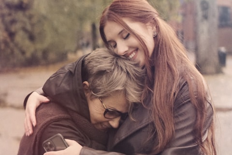 two women hugging each other on a city street